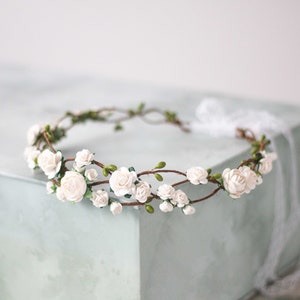 Off-white flower crown headband with small rose blossoms and green leaves