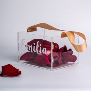 Personalized clear acrylic flower girl basket box with tan ribbon handle, holds rose petals; 'Emilia'.