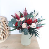 Preserved rose bouquet with red and pink roses and green foliage in white vase
