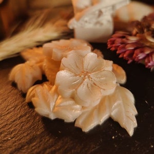 Flower-shaped wax melt with pale cream petals and embossed texture