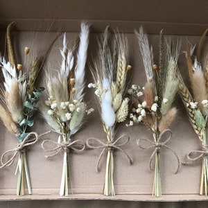 Dried flower posies set with white blooms and pampas feathers, tied with light ribbon