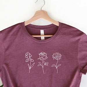 Purple crewneck T-shirt with small line-flower graphic across the chest