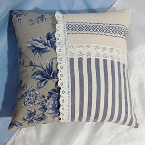 Blue and white striped throw pillow with lace edge and embroidered trim