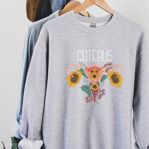 Light gray unisex sweatshirt with 'CUTERUS' text and colorful uterus graphic