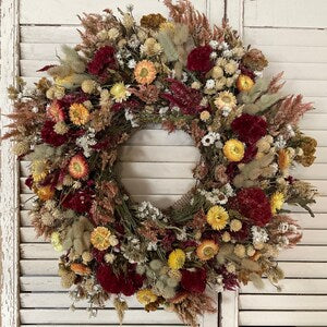 Handmade dried flower wreath with red, yellow, and tan everlasting blooms, round