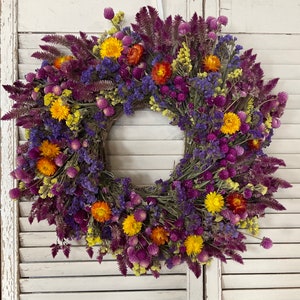 Dried flower wreath with purple blooms and yellow-orange flower heads, circular home decor