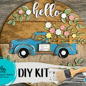 Wooden round door hanger DIY kit with blue old truck, flowers, and “hello” lettering
