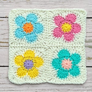 Cream crochet square with four flower motifs in blue, pink, yellow, and teal