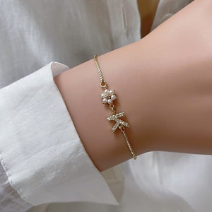 Gold-tone toddler bracelet with small flower charms, worn on a wrist