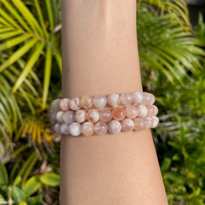 Pink agate bead bracelet with three stacked strands on a wrist