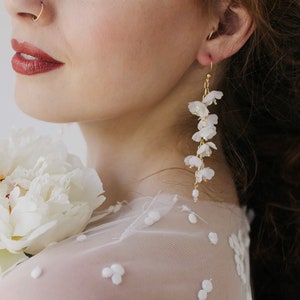 White floral drop earrings with layered blossoms and gold-tone hooks