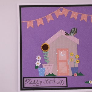 Floral birthday greeting card with garden scene, sunflowers, bird, and banner text