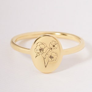Gold-tone birth flower ring with oval face and engraved floral bouquet