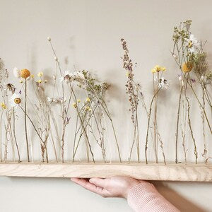 Dried wildflower stems on wooden base flower arrangement with grasses and daisies
