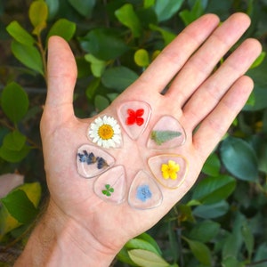 Resin flower guitar pick set with heart and colorful petals, shown on a hand
