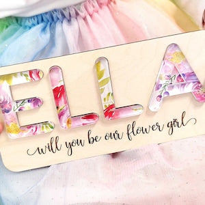 Flower girl name puzzle board with colorful letter cutouts and 'Will you be our flower girl' text.