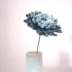 Crochet flower pattern with layered blue-gray blossoms on a thin green stem