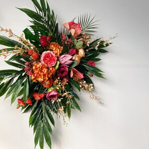 Tropical wedding floral bouquet with bright pink, red, and orange flowers and lush green leaves