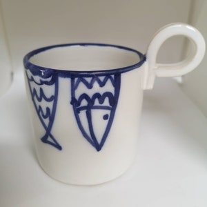 White ceramic mug with blue fish pattern and handle
