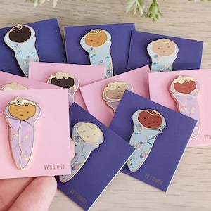 Cute baby-themed enamel pin on blue-and-pink card, cartoon baby in scrubs