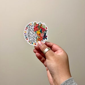 Floral brain-shaped sticker with red, yellow, and white flower details on dark outline