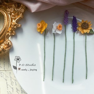 Handmade crochet flower bookmark with green stems, yellow, white, and purple blossoms