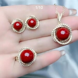Three-piece jewelry set with red round gemstone, silver-tone halo pendant, ring and studs