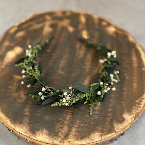 Green flower headband with small white blooms and eucalyptus-style leaves