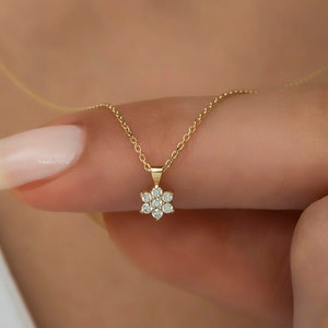 Gold diamond flower pendant necklace with small round stone petals on a thin chain
