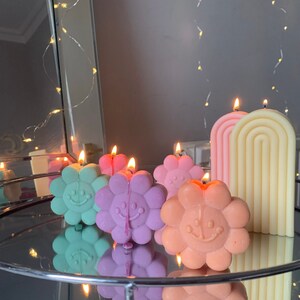 Cute flower-shaped candles in pastel colors with a tall striped candle on the side