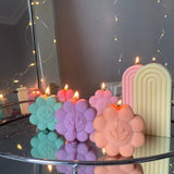 Cute flower-shaped candles in pastel colors with a tall striped candle on the side
