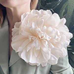 Large ivory fabric flower brooch with layered petals on dress