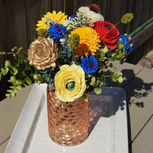 Gift bouquet in clear faceted vase with yellow, blue, and red flowers
