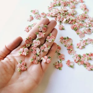 Tiny embroidered flower appliques: small pink and white floral patches with raised stitched detail