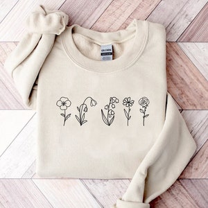 Cream sweatshirt with black line-art birth flower stems across the front