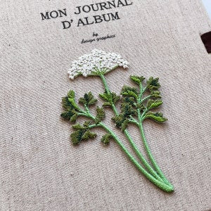 Embroidered flower iron-on patch with white blossoms and green leaves and stem