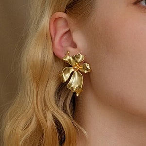 Gold floral stud earrings with layered flower shapes, small hoop-like back