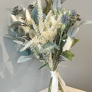 Artificial dried flower bouquet with white blooms and blue-gray leaves in a white vase