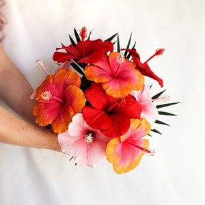 Handmade crepe paper hibiscus flower bouquet with red, pink, and orange blooms and green leaves