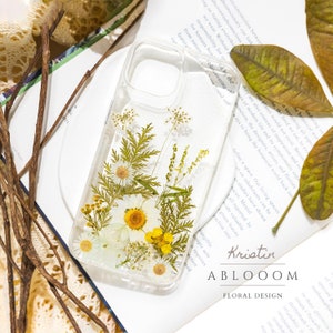 Pressed-flower phone case with clear background and yellow wildflower and green leaf design