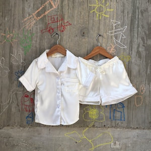 Pair of white satin pajama sets with button-up tops and shorts