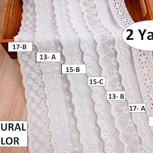 White cotton batiste fabric with scalloped lace-trim edge and broderie anglaise motifs