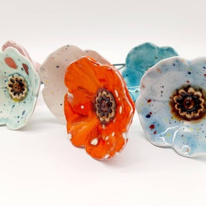 Ceramic poppy flower ornament with orange petals and dark center, speckled blue and white accents