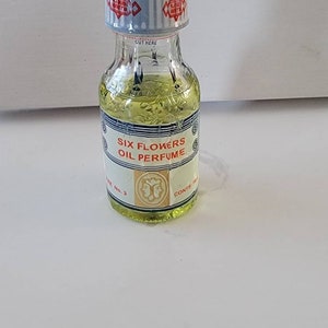 Six Flowers oil perfume bottle with clear glass and green liquid, front label