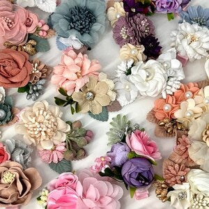 Assorted fabric flower hair clips with leaf accents in pastel and neutral tones