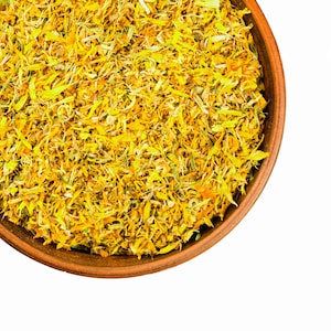 Dried edible calendula flower petals in a round bowl, yellow-gold flakes