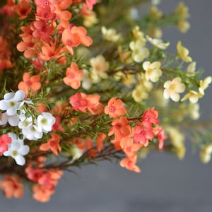 Colorful faux wildflower stems with small white, pink, orange, and yellow blooms