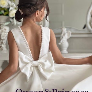 Ivory satin flower girl dress with pearl-trim V-back, bow waist and flowing skirt