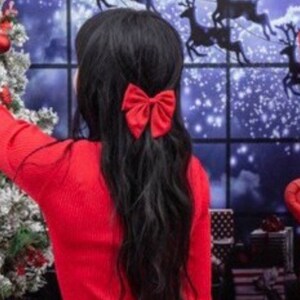Red bow hair clip on black hair with knot-style ribbon detail