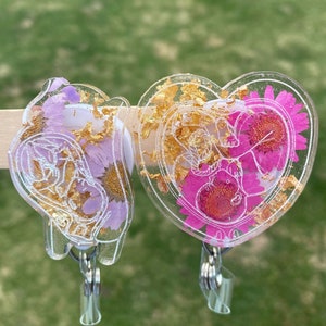 Heart-shaped badge reel pair with purple and pink charms, gold accents